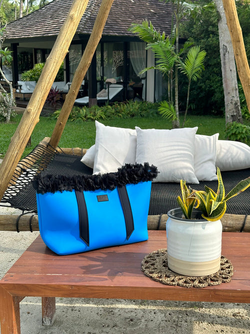 Blue bag with black trim on a wooden table outdoors