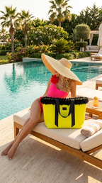 Woman in a swimsuit and sun hat sitting by a pool with a yellow bag.