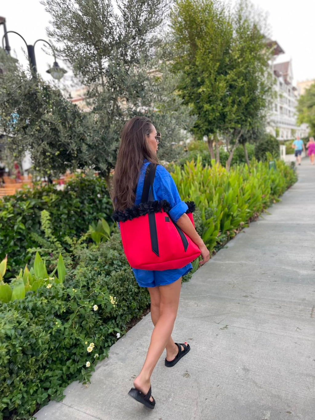Woman walking on a sidewalk with a red backpack