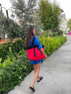 Woman walking on a sidewalk with a red backpack