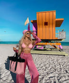 Woman in pink outfit on Miami Beach with colorful lifeguard stand in the background