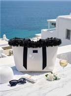 White tote bag with black trim on a table by the sea