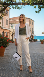 Woman in a stylish outfit standing on a cobblestone street with a scenic background.